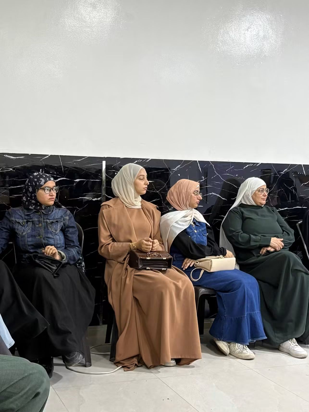 Four women seated along a wall as audience members at a screening