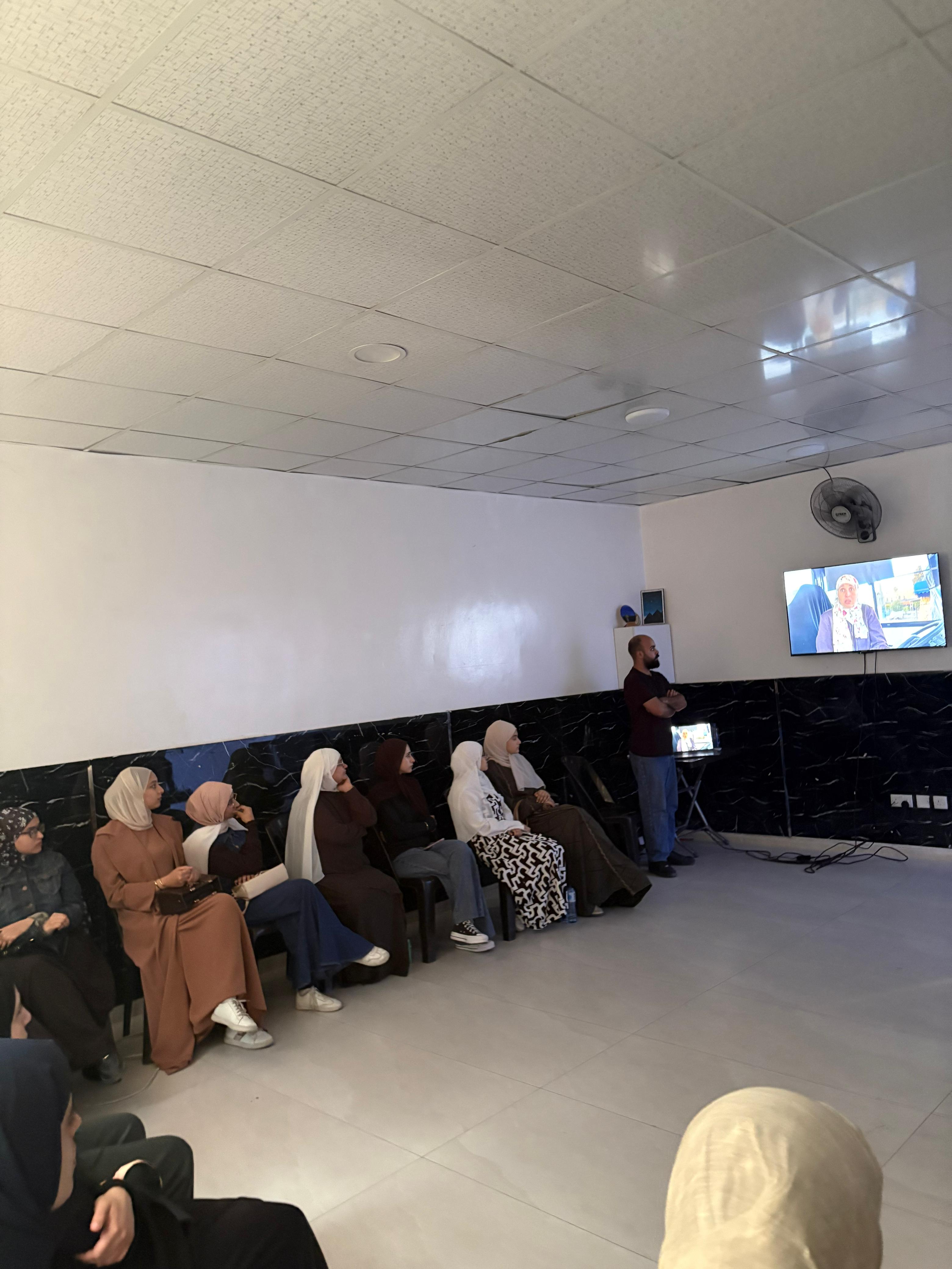 Women watching a film on a wall-mounted screen in a community centre