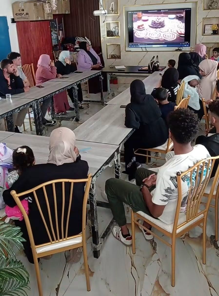 Families and community members watching a film together around long tables